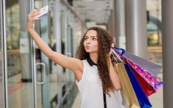 young woman taking selfie with shopping bags whilst pouting - signs of a try hard