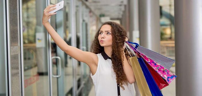 young woman taking selfie with shopping bags whilst pouting - signs of a try hard