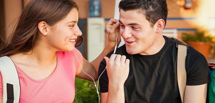 smiling young man and woman sharing headphone illustrating chemistry between people