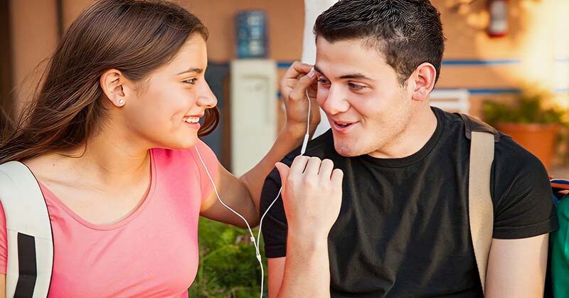 smiling young man and woman sharing headphone illustrating chemistry between people