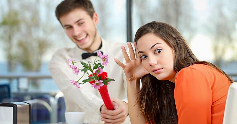 girl looking awkwardly away from a guy with flowers who is coming on too strong