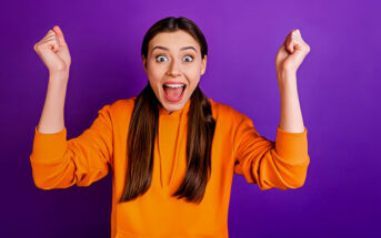 woman with excited face with clenched fists in the air illustrating how to be enthusiastic