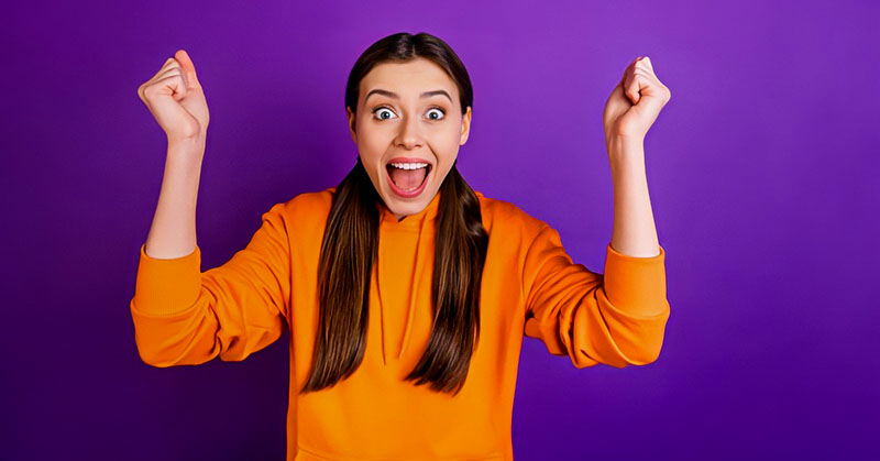 woman with excited face with clenched fists in the air illustrating how to be enthusiastic