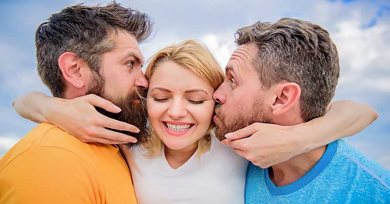 two men kissing each cheek of a woman illustrating an open relationship