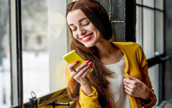 smiling woman looking at phone - illustrating texting too much before a first date