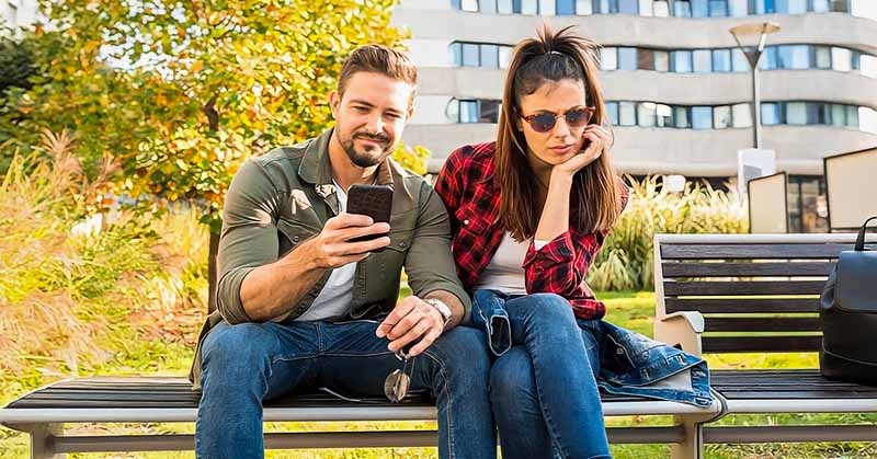 unromantic boyfriend on his phone ignoring his girlfriend