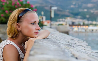 single woman looking out over harbor deciding whether to wait for a man she loves