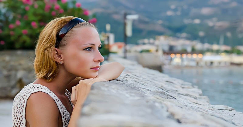 single woman looking out over harbor deciding whether to wait for a man she loves