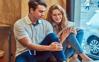 young guy and girl looking at tablet computer in a cafe