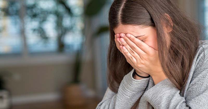 young woman with hands covering her face because she feels like she has ruined her life