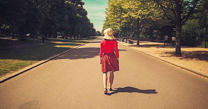 woman in red walking down an empty street - illustrating a life transition