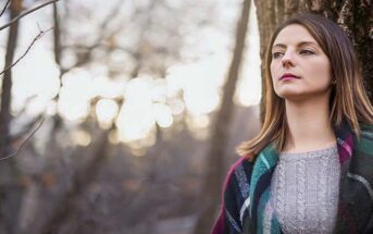 pensive looking woman standing in a forest thinking she needs a change in life