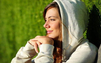 a young woman sitting with face toward the sun with a little smile on her face after rebooting her life