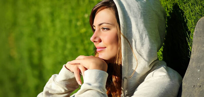 a young woman sitting with face toward the sun with a little smile on her face after rebooting her life