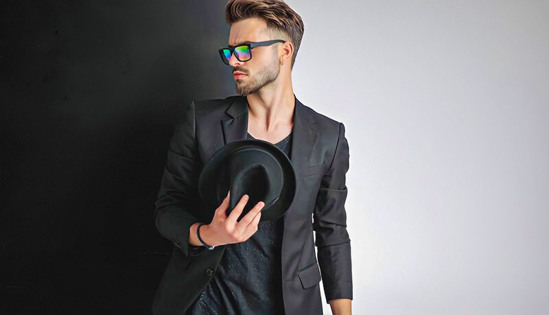 arrogant looking young man dressed in black with sunglasses and a hat - illustrating a bad boy