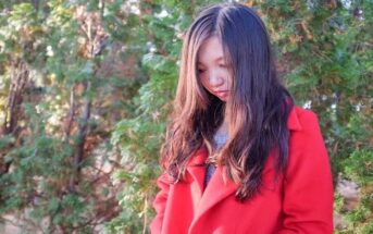 woman in red coat looking down illustrating that's she's got something on her mind