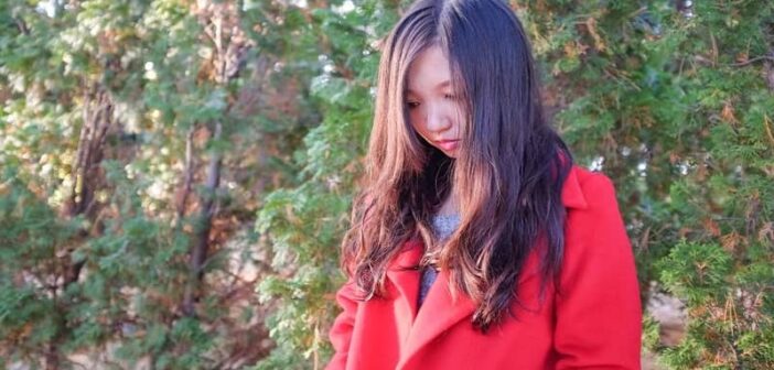 woman in red coat looking down illustrating that's she's got something on her mind