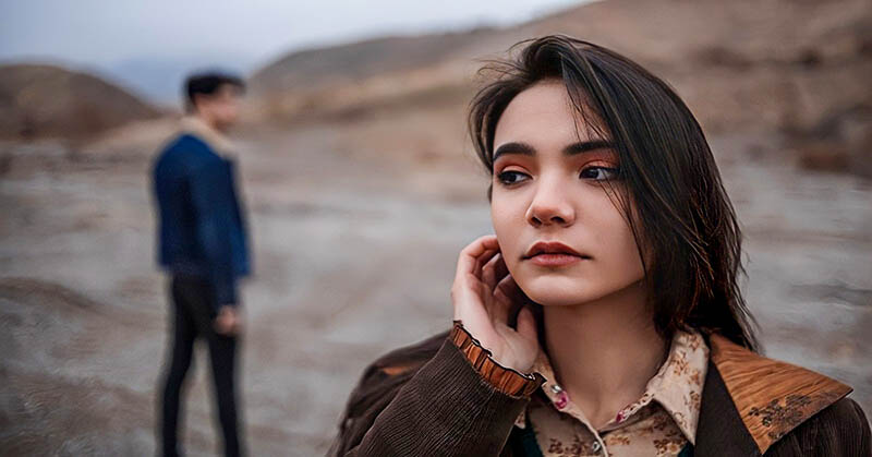 anxious woman in foreground with guy in the background - illustrating hot and cold behavior