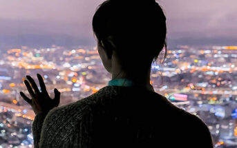 silhouette of woman looking out across city at night - illustrating destined to be alone forever