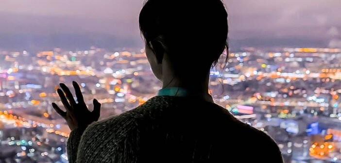 silhouette of woman looking out across city at night - illustrating destined to be alone forever