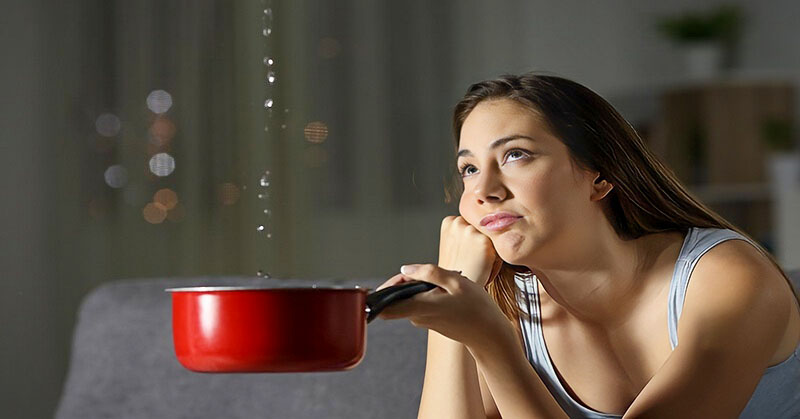 woman holding pan under leaking water from her ceiling - illustrating when nothing goes right