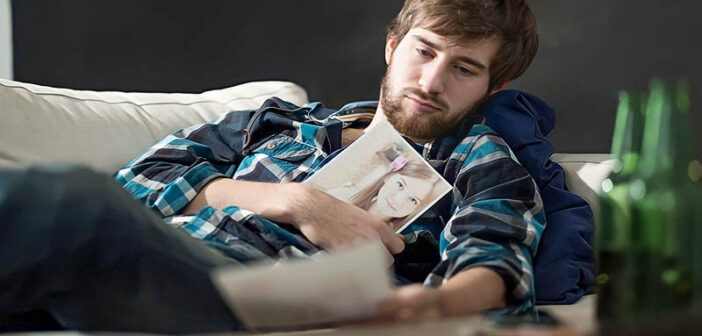 man looking longingly at photos of his ex because he still loves her