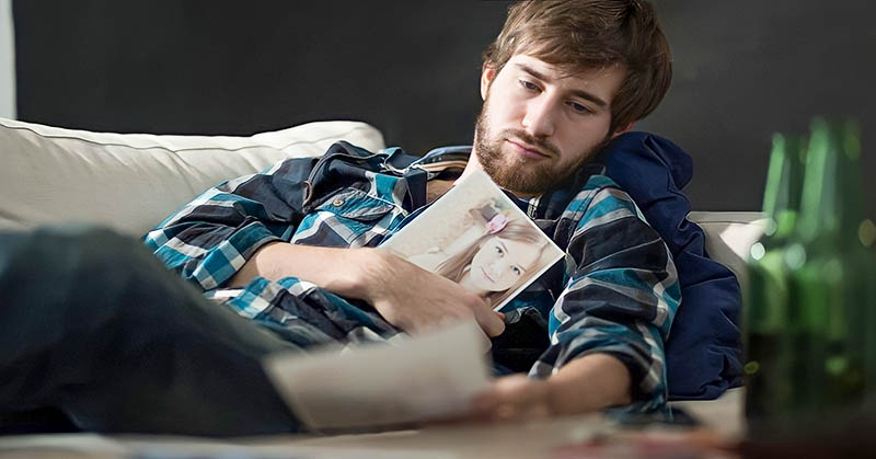 man looking longingly at photos of his ex because he still loves her