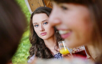 woman looking enviously at smiling person