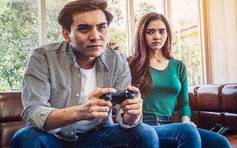 wife looking upset because she's not getting any attention from her husband who is playing video games