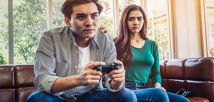 wife looking upset because she's not getting any attention from her husband who is playing video games