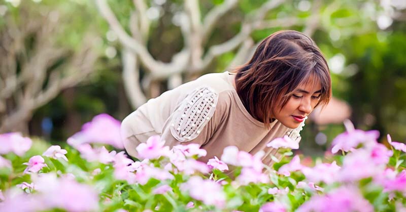 woman smelling some pink flowers - illustrating improving your quality of life