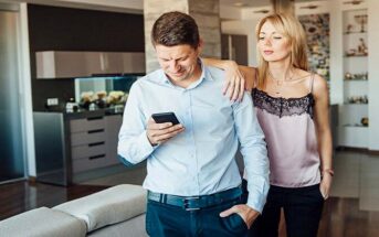 jealous wife looking over husband's shoulder at his phone