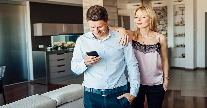jealous wife looking over husband's shoulder at his phone