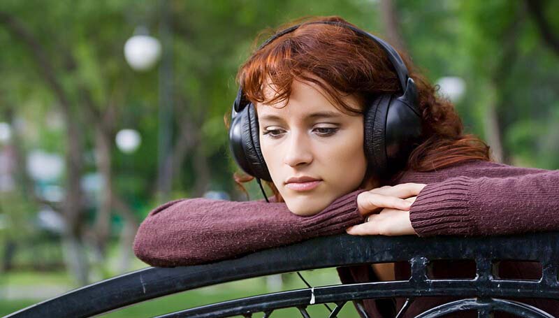 young pensive woman with headphones on trying to make a life-changing decision