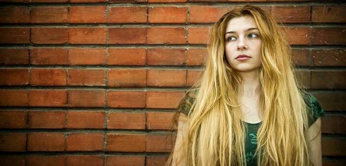 young unsatisfied woman standing in front of a brick wall