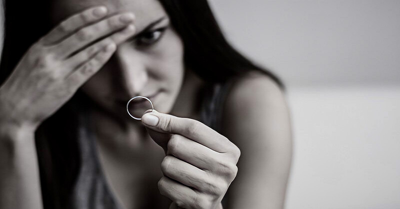 sad woman looking at wedding ring deciding when to walk away after infidelity