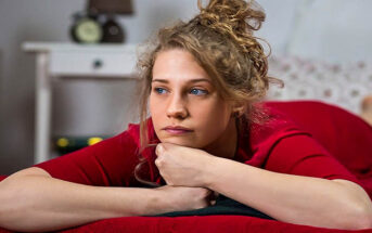 young woman looking very bored lying on her bed