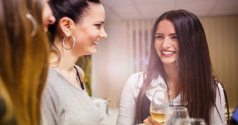 young woman being more outgoing and striking a conversation with two other women