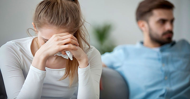 crying young woman getting no emotional support from her distant boyfriend