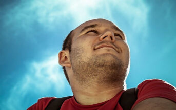 photo looking up at man against backdrop of a blue sky