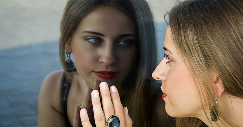 young woman looking at her reflection in a window, asking what kind of person she wants to be