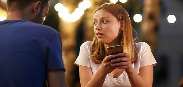 a young woman looking at her phone on a bad date - she hates dating
