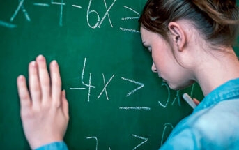 teenage girl with head against blackboard feeling dumb because of school