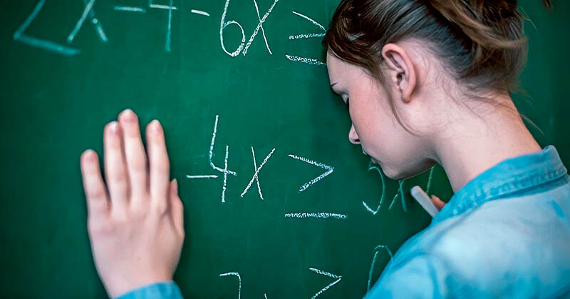 teenage girl with head against blackboard feeling dumb because of school