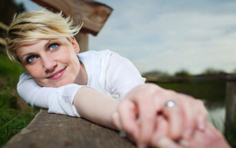 smiling woman laying on a bench - illustrating being your own best friend