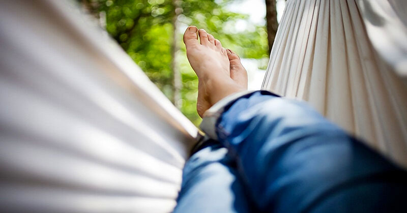 view of a person's legs and feet in a hammock - illustrating how to relax