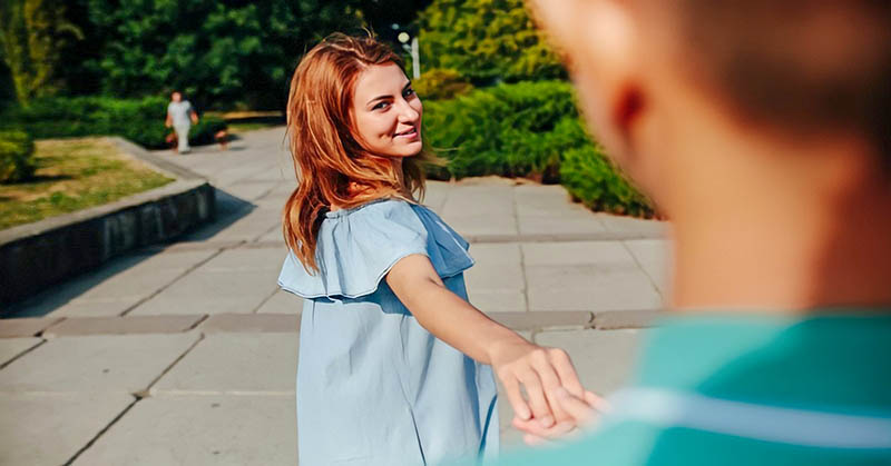 young woman leading a man by the hand