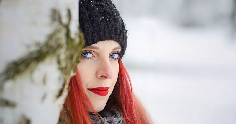 woman with red hair and red lipstick against a snowy backdrop