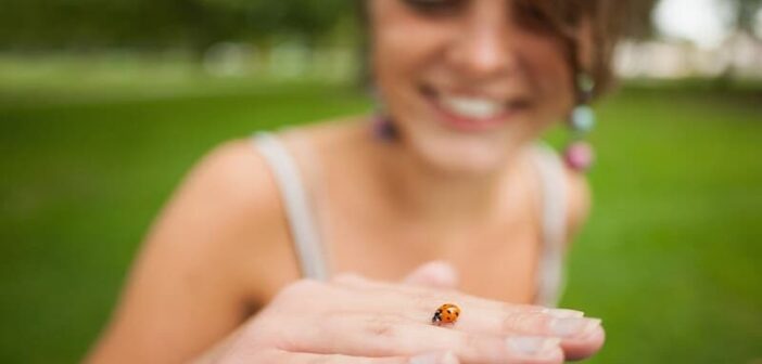 curious young woman holding a ladybird