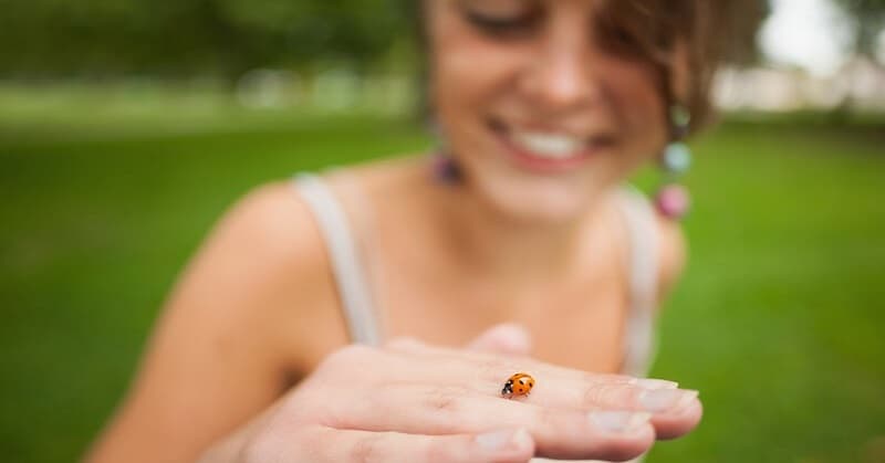 curious young woman holding a ladybird